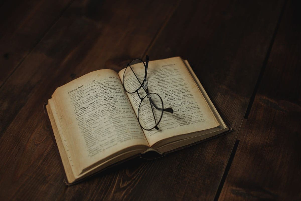 An open book with reading glasses resting on the page